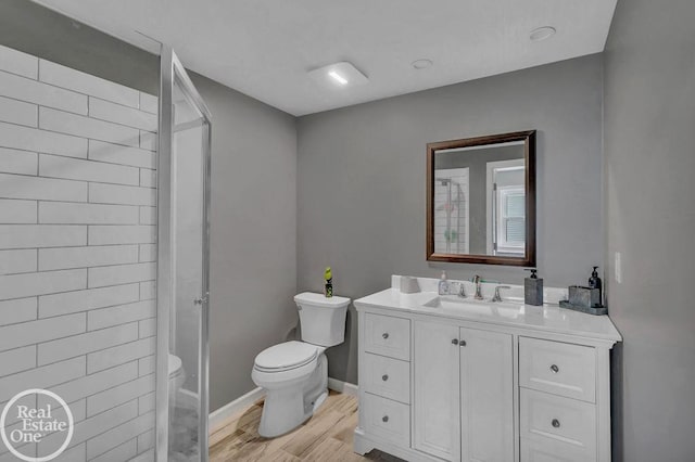 bathroom with walk in shower, wood finished floors, vanity, baseboards, and toilet