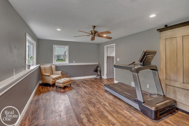 workout room with ceiling fan, a barn door, recessed lighting, baseboards, and wood finished floors