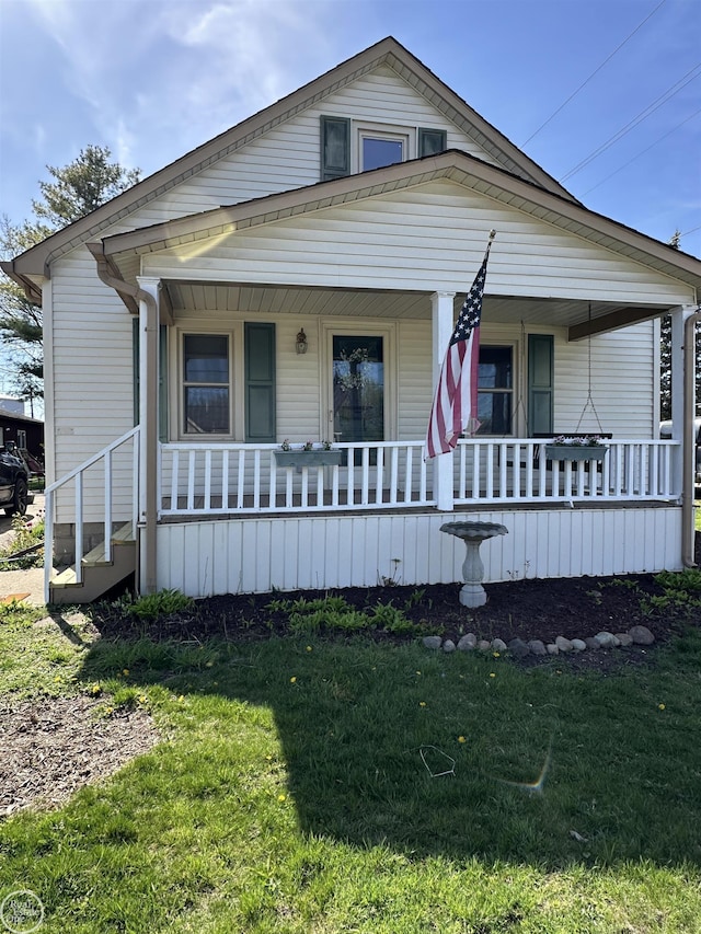 bungalow-style house featuring covered porch and a front yard