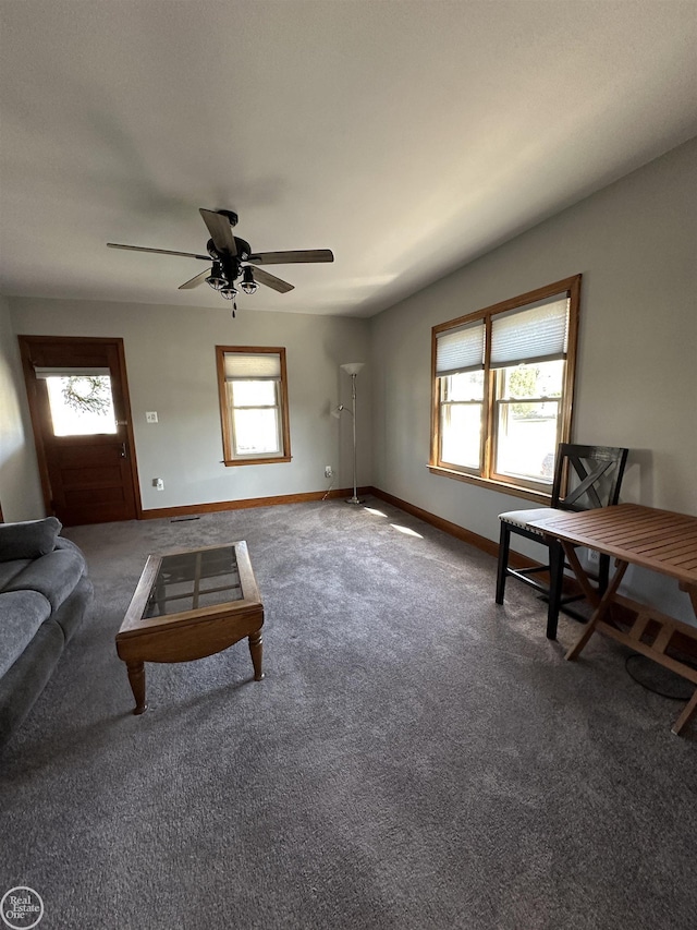 unfurnished living room with ceiling fan, baseboards, and carpet