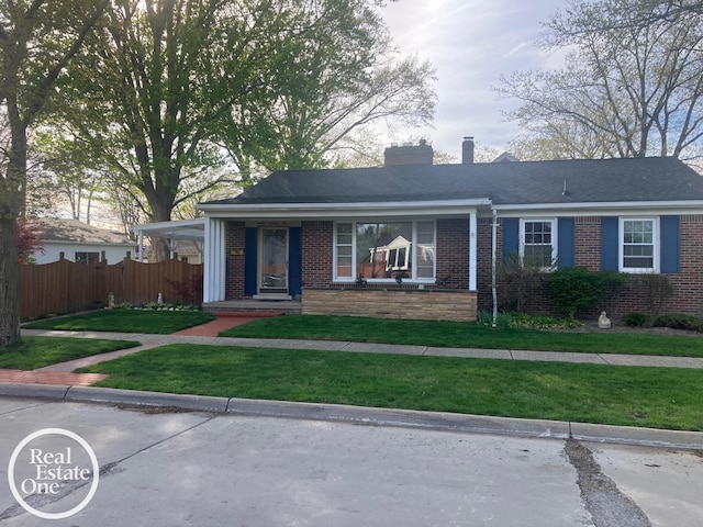 ranch-style home with brick siding, fence, a chimney, and a front lawn