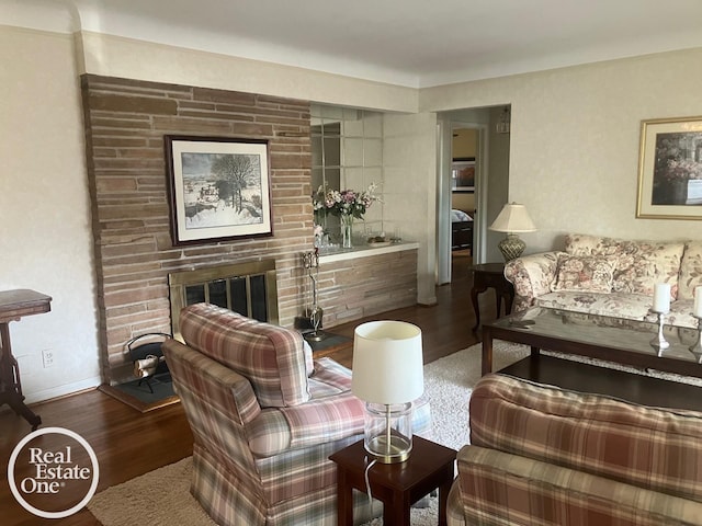 sitting room with baseboards, a brick fireplace, and wood finished floors