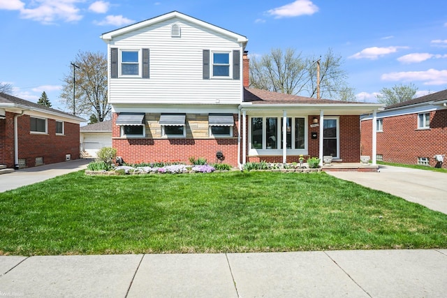 tri-level home with a detached garage, brick siding, an outdoor structure, and a front lawn