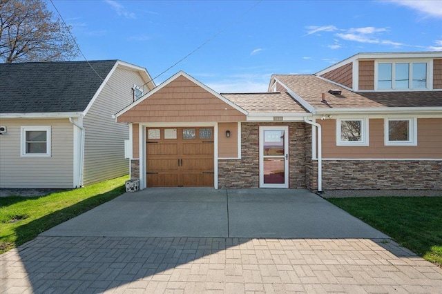 view of front of property featuring roof with shingles, driveway, stone siding, and a garage