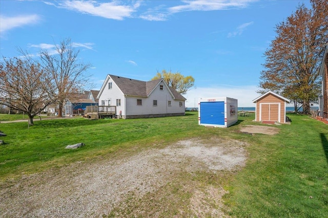 rear view of house featuring a wooden deck, an outdoor structure, a yard, and a shed
