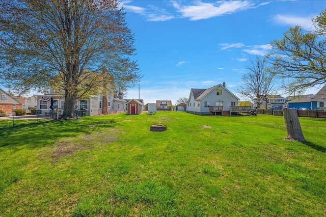 view of yard featuring a deck, a residential view, fence, an outdoor structure, and a shed