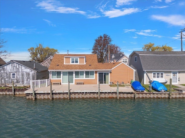 rear view of property with a shingled roof, a water view, and a sunroom