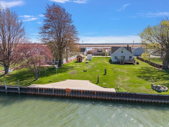rear view of property featuring a yard, a water view, a storage shed, and an outdoor structure