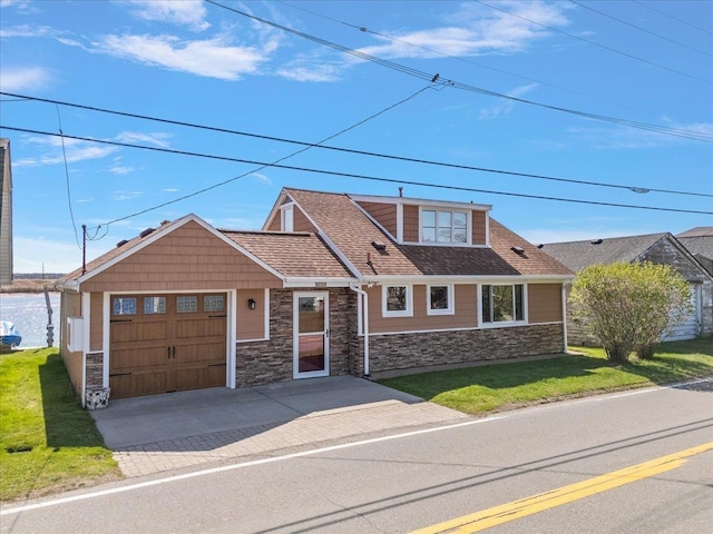 craftsman-style house featuring an attached garage, driveway, stone siding, and a front lawn