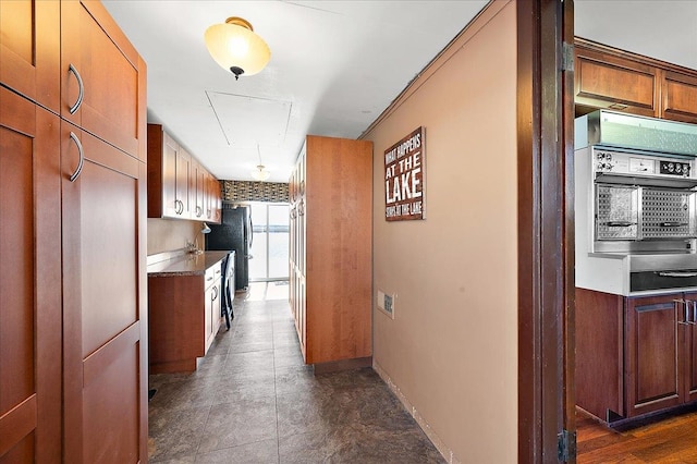 kitchen with baseboards, freestanding refrigerator, and brown cabinetry