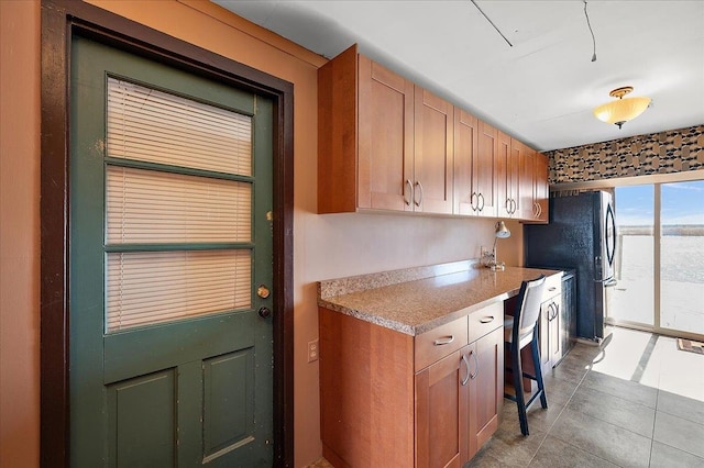 kitchen with light countertops, light tile patterned floors, and freestanding refrigerator
