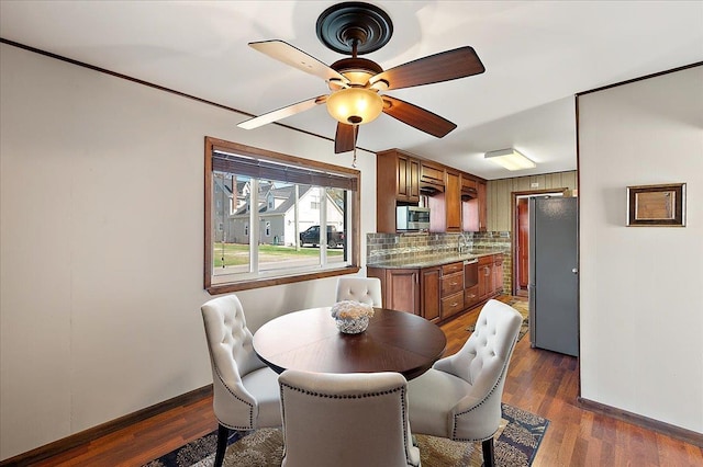 dining room featuring baseboards, a ceiling fan, and dark wood-type flooring