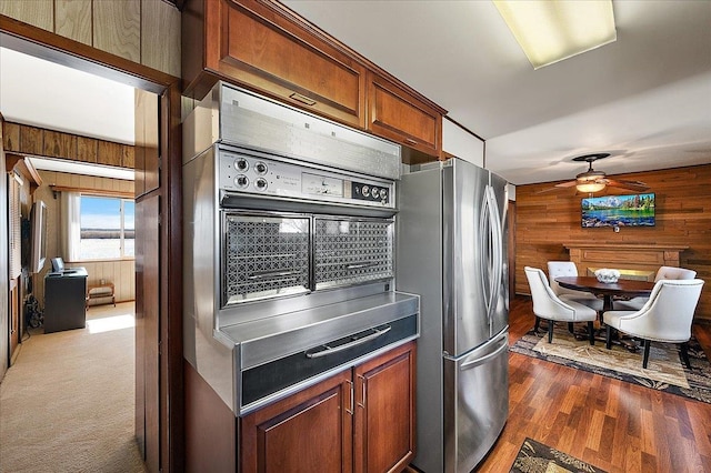 kitchen with dark wood-style flooring, ceiling fan, wood walls, freestanding refrigerator, and a warming drawer