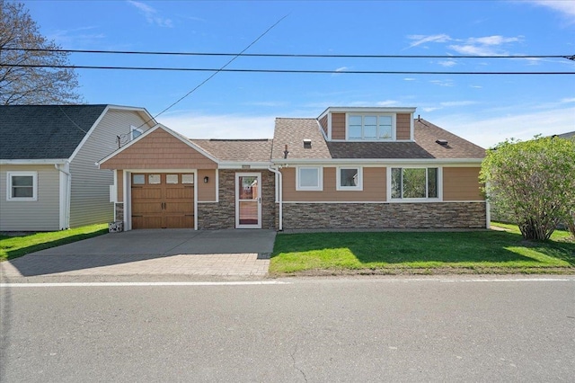 view of front of home featuring a front lawn, stone siding, roof with shingles, an attached garage, and driveway