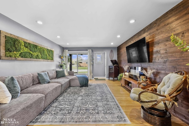living area featuring light wood-style floors, baseboards, wood walls, and recessed lighting