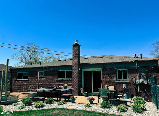 rear view of house with brick siding, outdoor lounge area, a chimney, and a patio area