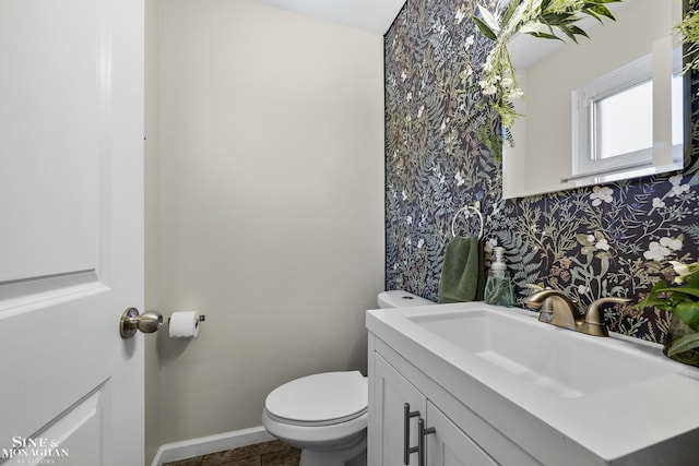 bathroom featuring vanity, baseboards, toilet, and wallpapered walls