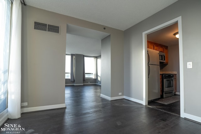 unfurnished living room featuring visible vents, baseboards, and dark wood-type flooring