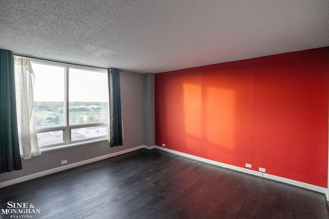 unfurnished room with a textured ceiling, baseboards, and dark wood-type flooring