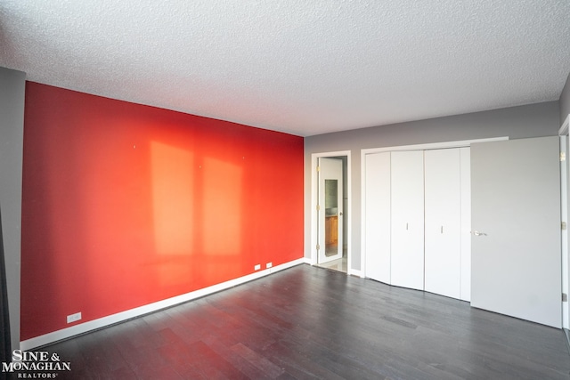 unfurnished bedroom featuring a textured ceiling, baseboards, a closet, and wood finished floors