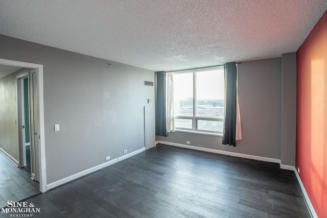 unfurnished room featuring baseboards, dark wood-style flooring, a textured ceiling, and visible vents