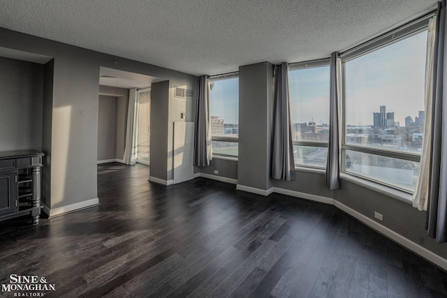 unfurnished living room with baseboards, a city view, a textured ceiling, and dark wood-type flooring