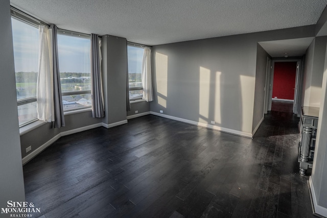 spare room with a textured ceiling, baseboards, and dark wood-type flooring