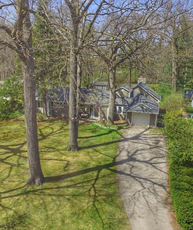 view of front of house with a garage, a chimney, driveway, and a front yard