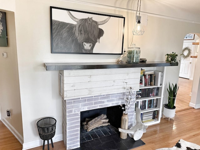 living room with arched walkways, baseboards, wood finished floors, and a fireplace