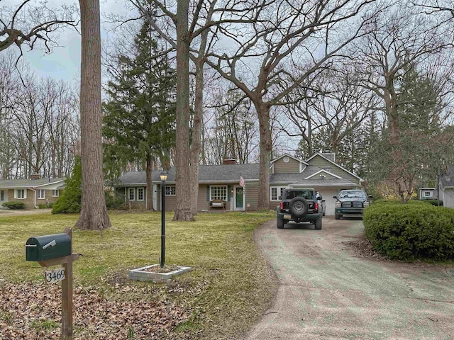 view of front facade featuring a chimney, a front lawn, and aphalt driveway