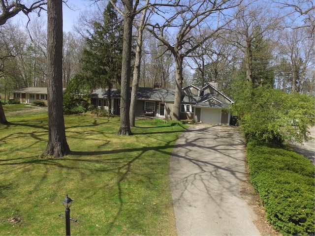 view of front of home with a garage, driveway, a chimney, and a front lawn