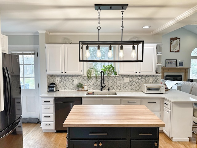 kitchen with stainless steel dishwasher, a sink, freestanding refrigerator, wood counters, and white cabinetry