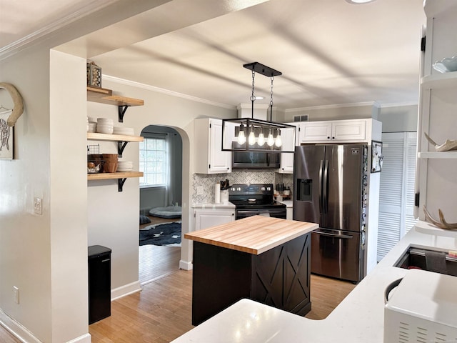 kitchen with ornamental molding, butcher block counters, white cabinetry, arched walkways, and stainless steel appliances