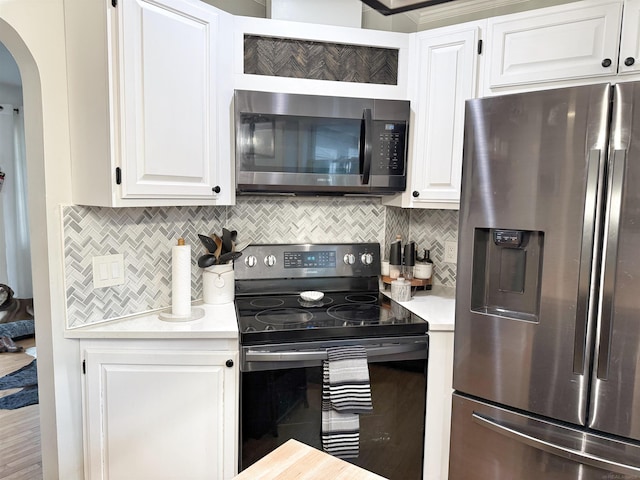 kitchen featuring light countertops, stainless steel appliances, arched walkways, and white cabinetry