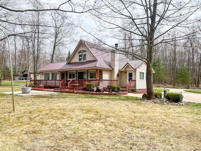 5421 Andrew St, Harrison, MI 48625 - view of front facade with a chimney, a front yard, metal roof, and a porch