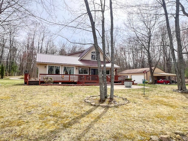 5421 Andrew St, Harrison, MI 48625 - view of front of house featuring a garage, an outbuilding, a front lawn, a wooden deck, and metal roof
