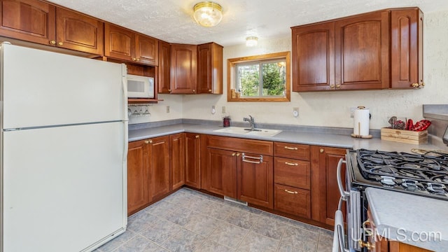 kitchen with a sink, light countertops, brown cabinets, and white appliances