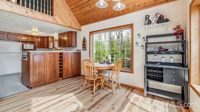 dining area featuring baseboards, lofted ceiling, and light wood-style floors