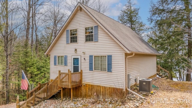 back of house featuring central AC unit, stairway, and a shingled roof