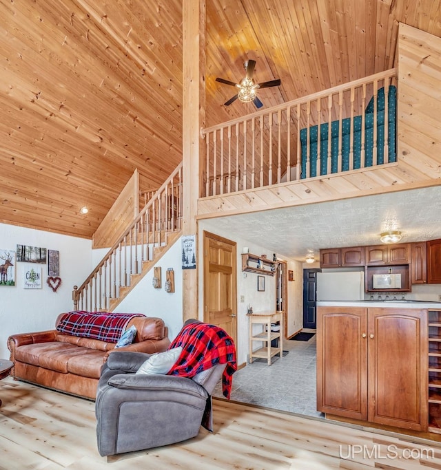 living room featuring ceiling fan, high vaulted ceiling, stairs, wood finished floors, and wood ceiling