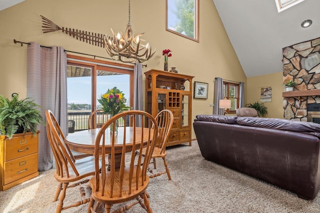 dining room with an inviting chandelier, light carpet, high vaulted ceiling, and a healthy amount of sunlight