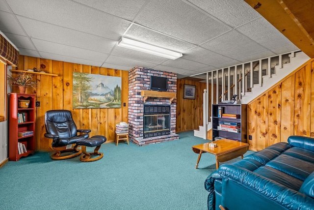 living area with carpet floors, a drop ceiling, wooden walls, and a fireplace