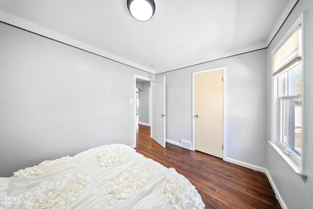 bedroom featuring baseboards, visible vents, multiple windows, and wood finished floors