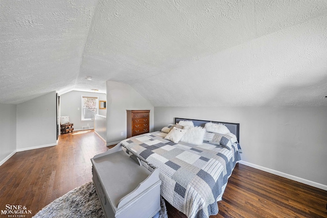 bedroom featuring baseboards, a textured ceiling, wood finished floors, and lofted ceiling