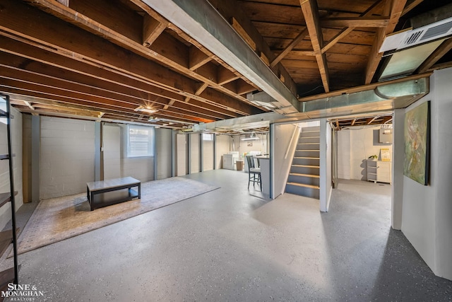 basement with visible vents, concrete block wall, washer and dryer, and stairway