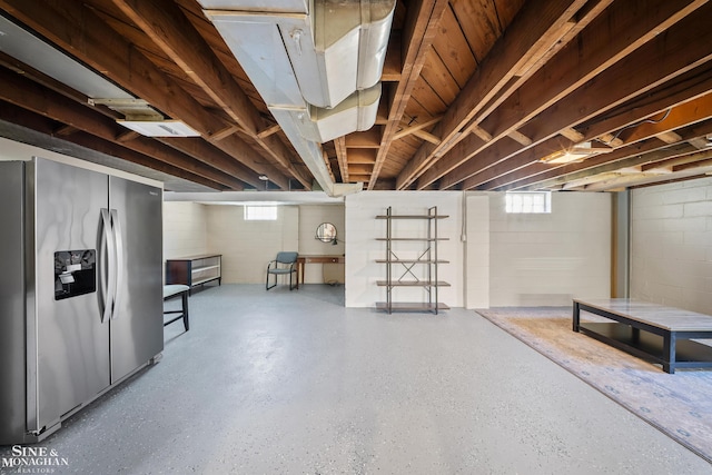 below grade area with stainless steel refrigerator with ice dispenser and concrete block wall
