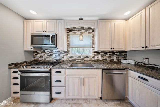 kitchen featuring a sink, dark stone counters, decorative backsplash, and stainless steel appliances