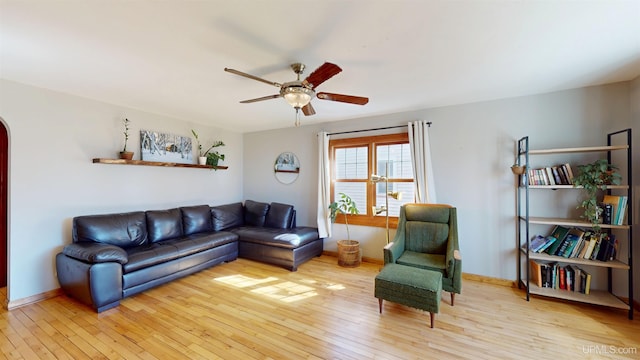 living area with baseboards, wood-type flooring, a ceiling fan, and arched walkways