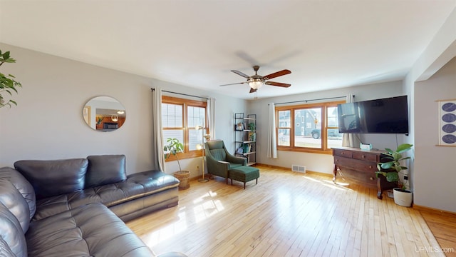 living area featuring baseboards, ceiling fan, light wood-style flooring, and visible vents