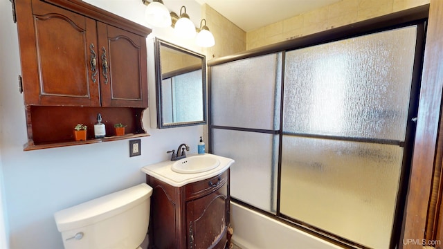 full bath with vanity, bath / shower combo with glass door, and toilet